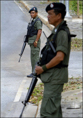 Security personel stand guard on the road to Be Tong in Southern Thailand. Seven people have been shot dead in Thailand's south, police said as the government stepped back from a controversial scheme to deny funding to Muslim villages seen as supporting insurgents.(AFP/File/Saeed Khan) 
