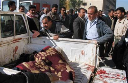 Unidentified Iraqi men grieve at the side of a pickup truck carrying one of the dead, after a man wearing a police uniform drove a car bomb inside the headquarters of police in Saddam Hussein's hometown of Tikrit in Iraq, setting off a massive explosion that killed at least 15 police and wounded 22 others Thursday, Feb. 24, 2005. [AP]
