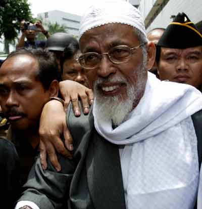 Indonesian Muslim cleric Abu Bakar Bashir is ushered out of a makeshift courtroom in Jakarta March 3, 2005. Fiery Muslim preacher Bashir was found guilty of an "evil conspiracy" to commit the 2002 Bali nightclub bombings by an Indonesian court on Thursday and sentenced to two and a half years in jail. [Reuters]