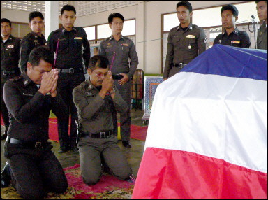 Thai policemen pray at the funeral of two colleagues at a Buddhist temple in Narathiwat province, southern Thailand. Six more people have been killed in the last three days in a string of shootings in Thailand's south, including a woman authorities described as the first female targeted by insurgents. [AFP]