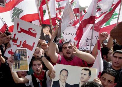 Demonstrators shout anti America slogans as they wave Lebanese flags and hold portraits of Syrian President Bashar Assad, right, Lebanese president Emile Lahoud and slain former Prime Minister Rafik Hariri in a central Beirut square, Lebanon, Tuesday March 8, 2005. Tens of thousands of pro-Syrian protesters gathered, answering a nationwide call by the militant Shiite Muslim Hezbollah group to demonstrate against foreign intervention and counter weeks of massive anti-Syrian rallies. (AP Photo/str) 