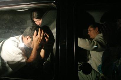 Herman Ramirez, left, one of several hostages who had been held captive at the Banco Nacional de Costa Rica in the tourist town of Monteverde, about 60 miles noth of the capital of San Jose, Costa Rica holds his head after escaping his captors Wednesday March 9, 2005. [AP]