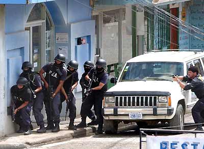 Police officers take up positions in front of the National bank where bank robbers took some 30 people hostage in Santa Elena, northwest of the capital San Jose, March 9, 2005. [Reuters]