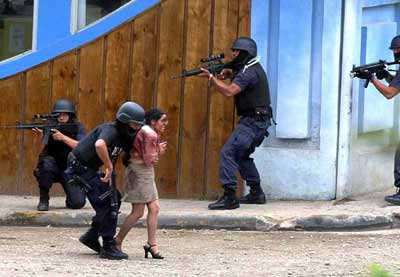 Police officers guard a hostage who escaped from a bank robber at the National banck in Santa Elena, northwest of the capital San Jose, March 9, 2005. [Reuters]