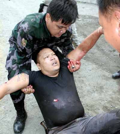 Philippine guards help an injured colleague after a gunbattle with inmates at a police camp in Manila March 14, 2005. Several Islamic radicals were holed up at a police camp in Manila on Monday after snatching weapons from their guards and shooting dead two of them in an escape attempt, Philippine police said. [Reuters]