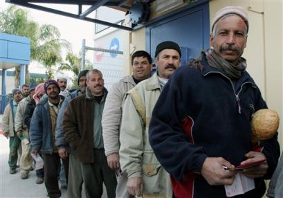A group of Palestinian workers working in Israel, wait to enter the Gaza Strip through the Erez border crossing Sunday March 13, 2005. Israel on Sunday permitted 1,400 more Palestinians to enter Israel, part of a gradual easing of restrictions after last month's Mideast summit. The entry permits were issued to 900 Palestinian merchants and business people from the West Bank and 500 from the Gaza Strip, bringing the total of Palestinians allowed to work in Israel to 9,800. [AP]