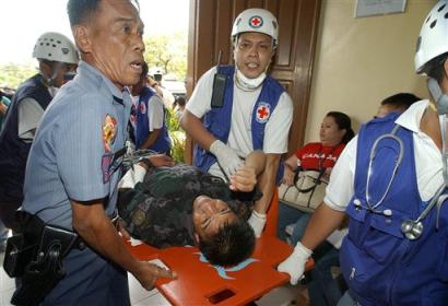 Rescuers carry a wounded policeman inside a hospital after he was hit during an assault inside a jail compound in suburban Taguig against armed suspected Abu Sayyaf prisoners on Tuesday March 15, 2005. At least seven people, including two muslim rebel leaders, have been killed so far as the alleged muslim rebels grabbed a gun, creating a stand-off between police and the suspects. (AP Photo/Pat Roque)