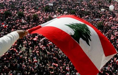 A protester waves a Lebanon flag above some thousands of Lebanese opposition protesters as they gather during a demonstration in Martyrs Square, central Beirut, Lebanon, Monday March 14, 2005. Hundreds of thousands of Lebanese people answered an opposition call for a massive protest to demand a full Syrian troop withdrawal, resignations of security chiefs and an international investigation into the death of former Premier Rafik Hariri.(AP Photo/Kevin Frayer) 