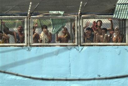 Filipino inmates shout for help as tear gas fills the air during an assault by policemen inside a jail compound in suburban Taguig, south of Manila, against armed suspected Abu Sayyaf prisoners on Tuesday March 15, 2005. [AP]