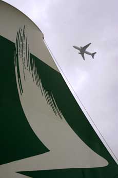 A plane flies past a plane-tail shaped Cathay Pacific Airways advertisement at the Hong Kong international airport March 16, 2005. Air China Ltd. may merge with Hong Kong's Cathay Pacific Airways Ltd. in a deal that would create a Chinese aviation powerhouse, a newspaper said on Wednesday