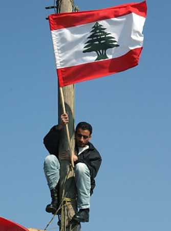 A Lebanese protester raises the country's flag near the Syrian intelligence offices in Beirut, March 15, 2005. Syrian intelligence agents began evacuating their headquarters in Beirut on Tuesday, partially meeting a key U.S. and Lebanese opposition demand for an end to three decades of Syrian tutelage over its neighbor. (Sharif Karim/Reuters) 