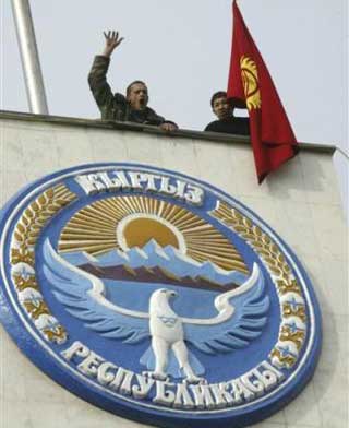 Two protesters with the Kyrgyz state flag, stand on a roof of government headquarters in Bishkek, Kyrgyzstan, Thursday, March 24, 2005. Protesters stormed the government and presidential compound in Kyrgyzstan on Thursday, entering the building after clashing with riot police who had surrounded it during a large opposition rally and march. [AP] 