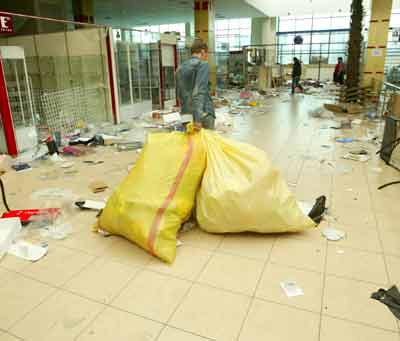 A Shop assistant drags bags through the debris of the shopping center in central Bishkek, March 25, 2005. A Kyrgyz opposition leader called for calm on Friday after protests that plunged into violence and looting and left the capital strewn with broken glass and blood. [Reuters]