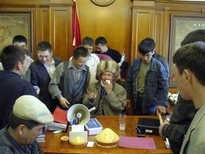Kyrgyz opposition supporters gather in President Askar Akayev's office in Bishkek, Kyrgyzstan, Thursday, March 24, 2005. An opposition leader, Ulan Shambetov, center background, sits Akayev's chair. Protesters stormed the presidential compound, seizing control of the main seat of state power after clashing with riot police, and President Askar Akayev reportedly resigned from office. (AP Photo/Azamat Imanaliev, AKIpress) 