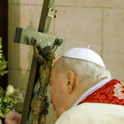 Pope John Paul II hugs a cross as he watches from his Vatican apartment via television the "Via Crucis" (Way of the Cross) procession at Rome's ancient Colosseum, March 25, 2005. Pope John Paul, whose illness has prevented him from leaving the Vatican, on Friday night used a video link to join a traditional Via Crucis (Way of the Cross) procession in Rome. It was the first time in his papacy, now in its 27th year, that the 84-year-old Pope has missed the procession around Rome's ancient Colosseum which commemorates the last hours in Christ's life. [Reuters]