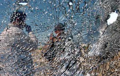 Members of the Iraqi Facilities Protection Service (FPS), viewed through a shattered windshield of a vehicle, survey the damage at the scene of a firefight in the town of Rabia in northern Iraq (news - web sites) March 25, 2005. Members of the Kurdish Peshmerga militia opened fire at nearby FPS forces after they came under a roadside bomb attack, sparking a firefight, which led to the death of five policemen and two FPS members on Thursday night in Rabia, according to police sources. (Namir Noor-Eldeen/Reuters) 