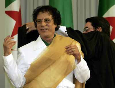 Chief administrative officer of Algiers's University Tahar Hadjar (R) helps the Libyan leader Muammar Gaddafi to put a cape on as a symbol of the Doctorate Honoris Causa the University of Algiers has awarded him at the Nations Palace in Algiers, March 27,2005. [Reuters]