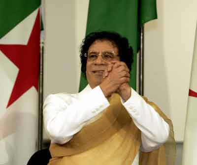 Libyan leader Muammar Gaddafi gestures as he greets the audience at the Nations Palace in Algiers, March 27,2005. The Libyan Leader who came to the Algerian capital to attend the Arab countries summit at the beginning of the week, was awarded a Doctorate Honoris Causa by an Algiers University. [Reuters]