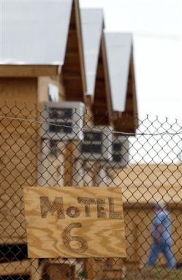 A handmade wooden sign reading 'Motel 6' is hung on the fence of Camp Alpha in the U.S. Naval Base at Guantanamo Bay, Cuba in this April 7, 2002 file photo. The arrival of hundreds of terror suspects at this remote U.S. naval outpost in the Caribbean not only lifted it from obscurity but produced a population boom and a flood of things to keep its new residents happy: a miniature golf course, Starbucks coffee, a Go-Cart track and music concerts. (AP Photo/Beth A. Keiser, file) 