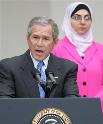 President Bush makes remarks on freedom and democracy, Tuesday, March 29, 2005, in the Rose Garden at the White House. Bush was surrounded by Iraqi nationals, some who live in the United States, who voted in the recent Iraqi elections. At right is Ilham al-Jawahiri. [AP]