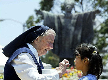 A nun gives the host to a girl during a mass in honour of Pope John Paul II in Guatemala City.(AFP/Orlando Sierra)