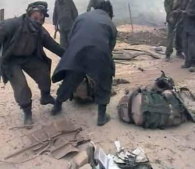 Afghans pull the body of a U.S. soldier clear of the remains of a U.S. military helicopter which crashed during a dust storm in Ghazni province, 120 km (80 miles) southwest of the capital of Kabul in this image taken from television footage April 6, 2005. The U.S. military helicopter crashed during a dust storm while on a routine mission in Afghanistan on Wednesday, killing at least 16 people on board, the military said in a statement. [Reuters]