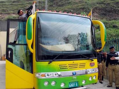 A Pakistani Kashmiri driver of a bus adjusts a Pakistani flag before departure from a bus terminal in Muzaffarabad, in Pakistan-controlled Kashmir, April 7, 2005. A bus garlanded with orange marigolds set off from the capital of Indian-controlled Kashmir on Thursday carrying passengers bound for the Pakistani side of the territory for the first time in nearly 60 years. The bus, launching a historic service linking the Himalayan region divided since 1947, was sent off by Indian Prime Minister Manmohan Singh from Kashmir's main city Srinagar, bound for Muzaffarabad. REUTERS/Amiruddin Mughal 