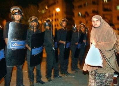 An Egyptian woman walks past Egyptian police officers who are securing the area near al-Hussein hospital in Cairo Thursday April 7, 2005 after people injured in a bomb explosion were taken there for treatment. The explosion, apparently set off by a man on a motorcycle hit an outdoor bazaar popular with tourists in Cairo's Old City, killing two people including a French woman, and wounding 20 others, officials said. (AP Photo/Amr Nabil) 