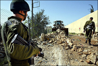 An Israeli soldier stands guard as a military bulldozer removes a roadblock at the entrance to the West Bank village of Jabaa. Israeli Defence Minister Shaul Mofaz decided that the homes of the Jewish settlers who are to be uprooted from the Gaza Strip will not be demolished.(AFP/Pedro Ugarte) 
