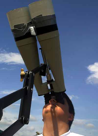 Juan Manuel observes a hybrid Solar Eclipse over Penonome, in the province of Cocle, Panama, April 8, 2005. [Reuters]