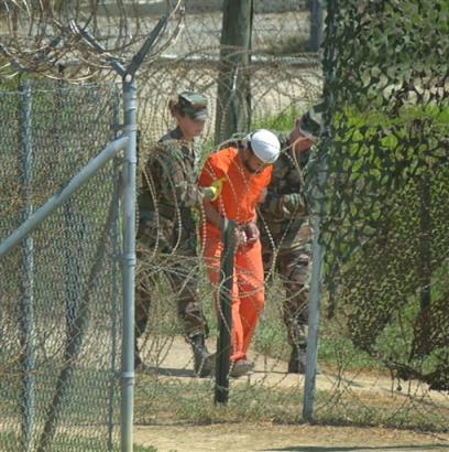 A detainee is escorted to interrogation by U.S. military guards at Camp X-Ray at Guantanamo Bay U.S. Naval Base, Cuba, on Wednesday, Feb. 27, 2002. The government is holding about 550 terrorist suspects at the U.S. Navy base in Cuba. An additional 214 have been released since the facility opened in January 2002 _ some into the custody of their home governments, others freed outright. (AP Photo/Andres Leighton, File)