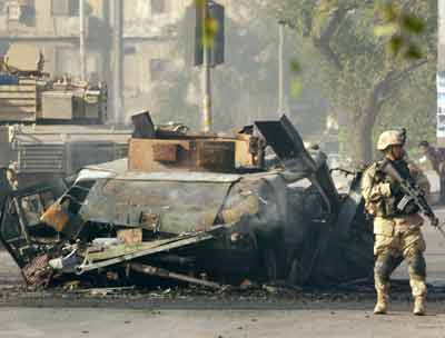 A U.S. Army soldier stands guard next to a destroyed U.S. military Humvee after an attack in southeast Baghdad April 13, 2005. The attack left the vehicle in flames, a Reuters witness said. There were no immediate reports on casualties. [Reuters]