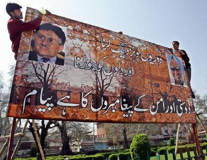 Kashmiris install a hoarding with pictures of Indian Primer Minister Manmohan Singh (R) and Pakistan President Pervez Musharraf (L) and with a message for peace in Urdu days before the start of the first historic bus service between the capitals of Indian and Pakistan administered Kashmir, in Srinagar April 2, 2005. REUTERS