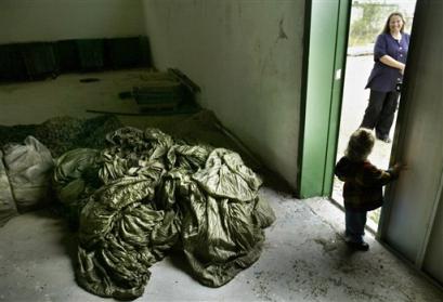 Gaza settler Datya Yitzhaki is seen outside a warehouse as a pile of tents collected by and her husband is seen inside in the Jewish settlement of Neve Dekalim Wednesday April 13, 2005. Jewish settlers said Wednesday they plan to bring thousands of supporters to the Gaza Strip for the upcoming Passover holiday, and that they have collected hundreds of tents to allow many of the visitors to remain to resist this summer's planned evacuation from the Gaza Strip and four West Bank settlements. (AP Photo/Oded Balilty) 