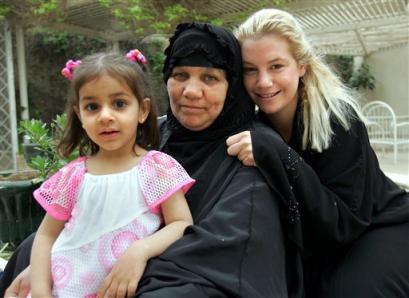 In this photo released by World Picture News on Sunday April 17 2005, American civilian Marla Ruzicka, of the Washington DC-based human rights group Civic Worldwide, poses with an Iraqi family that was helped by her organization in Baghdad, Iraq, Friday, April 15, 2005. Ruzicka was killed by a car bomb attack in Baghdad Saturday, April 16, 2005. (AP Photo / Scott Nelson, World Picture News, ho) 