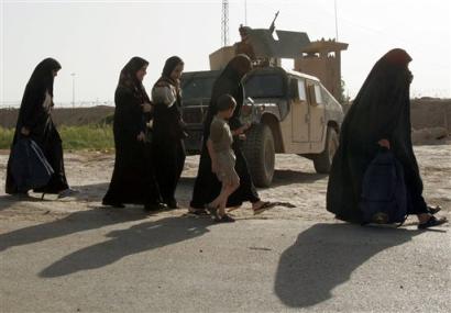 Iraqis walk past a U.S. military Humvee on their way out of Madain, Iraq Sunday, April 17, 2005. Iraqi security forces raided the central Iraqi town Sunday, where Sunni militants were holding dozens of Shiite Muslims hostage and threatening to kill them unless all Shiites left the area, an Iraqi official said.(AP Photo/Khalid Mohammed)