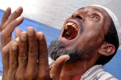 A man weeps and raises his hands in prayer for his lost brother near the collapsed nine-story garment factory near the Bangladeshi capital Dhaka, April 15, 2005. Rescuers pulled out six more decomposed bodies on Friday from the stench-filled ruins of the factory, taking the death toll to 50, officials and rescuers said. REUTERS