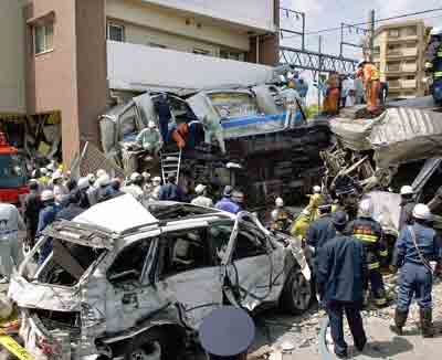 Rescue personnel work at the site of a derailed commuter train that smashed into an apartment building in Amagasaki, western Japan, April 25, 2005. Sixteen people were killed and at least 185 were injured when a commuter train derailed and smashed into an apartment building in western Japan on Monday, public broadcaster NHK reported. [Reuters]