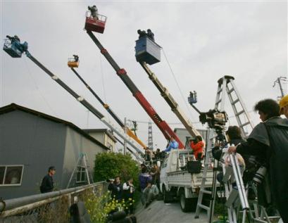 Japanese media use crane vehicles to film an accident site in Amagasaki, western Japan Tuesday morning, April 26, 2005. A packed commuter train jumped the tracks on Monday and hurtled into an apartment complex, killing at least 71 people and injuring more than 440 others in the deadliest Japanese rail accident in four decades. (AP