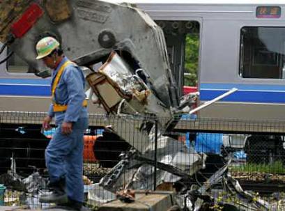 A worker walks past as a machine removes the wreckage of a derailed train at the site of the train that smashed into an apartment building in Amagasaki, western Japan April 26, 2005. Police looking for clues to the cause of Japan's worst rail crash in over 40 years raided the offices of the train's operator as weeping relatives claimed the remains of many of the 73 confirmed dead. (Issei Kato/Reuters)