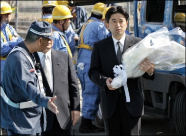 A man carries a bouquet of flowers for victims of a train crash in Amagasaki city near Osaka, western Japan. Rescue teams on their hands and knees worked their way into the most mangled pieces of Japan's massive train wreck in a last-ditch hope to find survivors as the death toll rose to 103(AFP