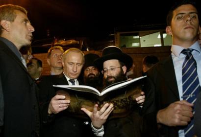 Russian President Vladimir Putin, center left, looks at a book with Rabbi Shmuel Rabinovitch, right as he visits at the Western Wall, not seen, Judaism's holiest site, in Jerusalem's Old City, Wednesday, April 27, 2005.