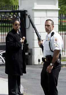 A uniformed Secret Service officer toting a shotgun stands guard inside the northwest gate of the White House during a security alert, April 27, 2005. The alert was raised on fears that an unidentified aircraft had entered restricted space near the White House, prompting President Bush to move to an underground shelter. The alert lasted a few minutes before officials determined it was a false alarm. 