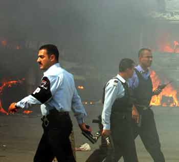 A group of Iraqi policemen walk near a burning car in central Baghdad May 10, 2005. A suicide car bomber blew up his vehicle near a U.S. military convoy in central Baghdad on Tuesday, killing at least seven Iraqis and wounding 16, police said. [Reuters]