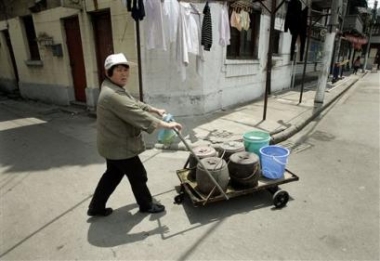 A resident carries chamber pots Tuesday May 10, 2005 in Shanghai, China.