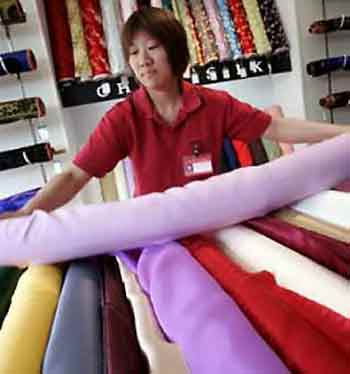 A Chinese shopkeeper arranges textile materials in a shop at the Nanjing Road shopping area in Shanghai, China, May 10, 2005. (Mark Ralston/Reuters)