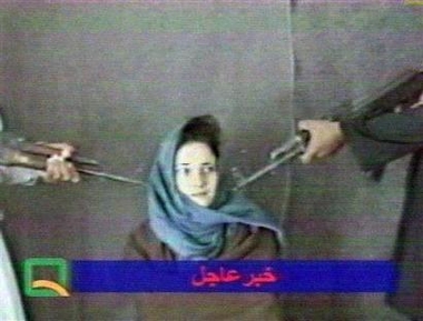 Italian aid worker Clementina Cantoni sits between two men holding assault rifles pointed at her head in this frame taken from video broadcast by an Afghanistan television station Sunday May 29, 2005.