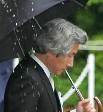 Japanese Prime Minister Junichiro Koizumi walks with an umbrella as rain water pooled on a tent pours down on him after offering a prayer at Chidorigafuchi National Cemetery for unknown soldiers in Tokyo, Japan's only nonreligious facility for war dead, Monday, May 30, 2005, two and a half months ahead of the 60th anniversary of the end of World War II.
