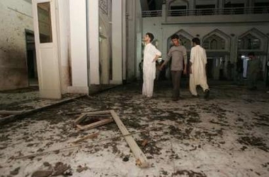 Pakistani Muslims look at a damaged portion of a mosque after a suicide bomb attack in Karachi May 30, 2005.