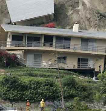 Rescue workers look over houses that were knocked off their foundations after an early morning landslide in Laguna Beach, California, June 1, 2005.